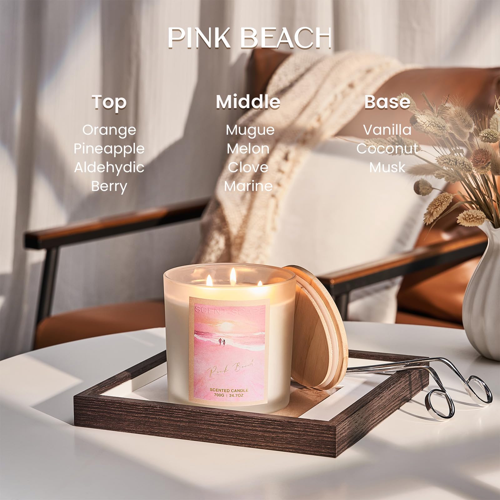 Candle with 'Pink Beach' fragrance description on a table with a chair and decorative elements.