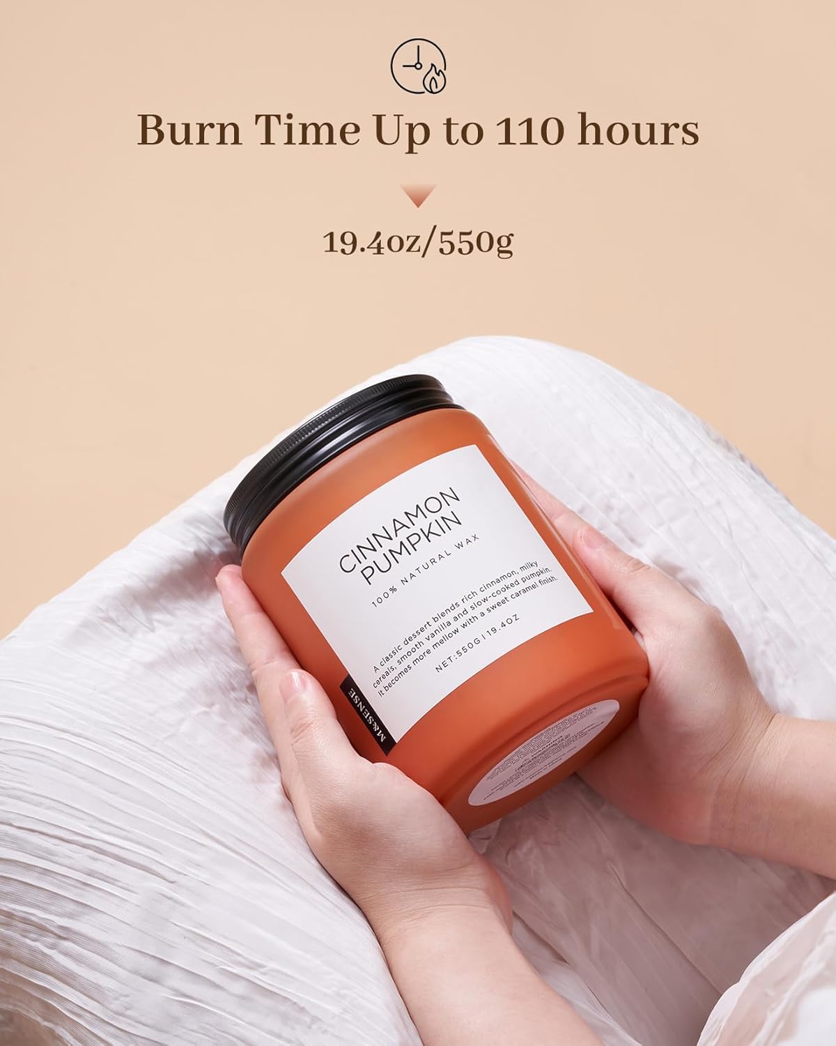 Candle labeled 'Cinnamon Pumpkin' held by a hand with a beige background