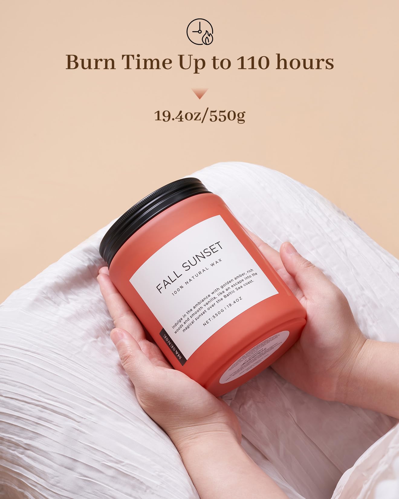 Candle labeled 'Fall Sunset' held by a person with a beige background