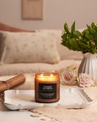 Candle labeled 'Fireside Bourbon' on a tray with flowers and a vase in a cozy living room setting.