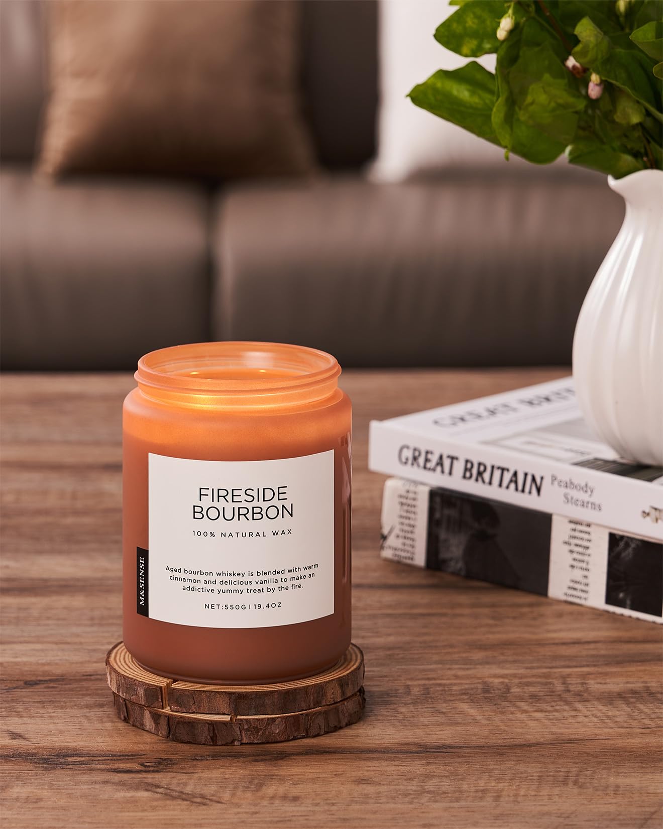 Fireside Bourbon candle on a wooden coaster with a couch and books in the background