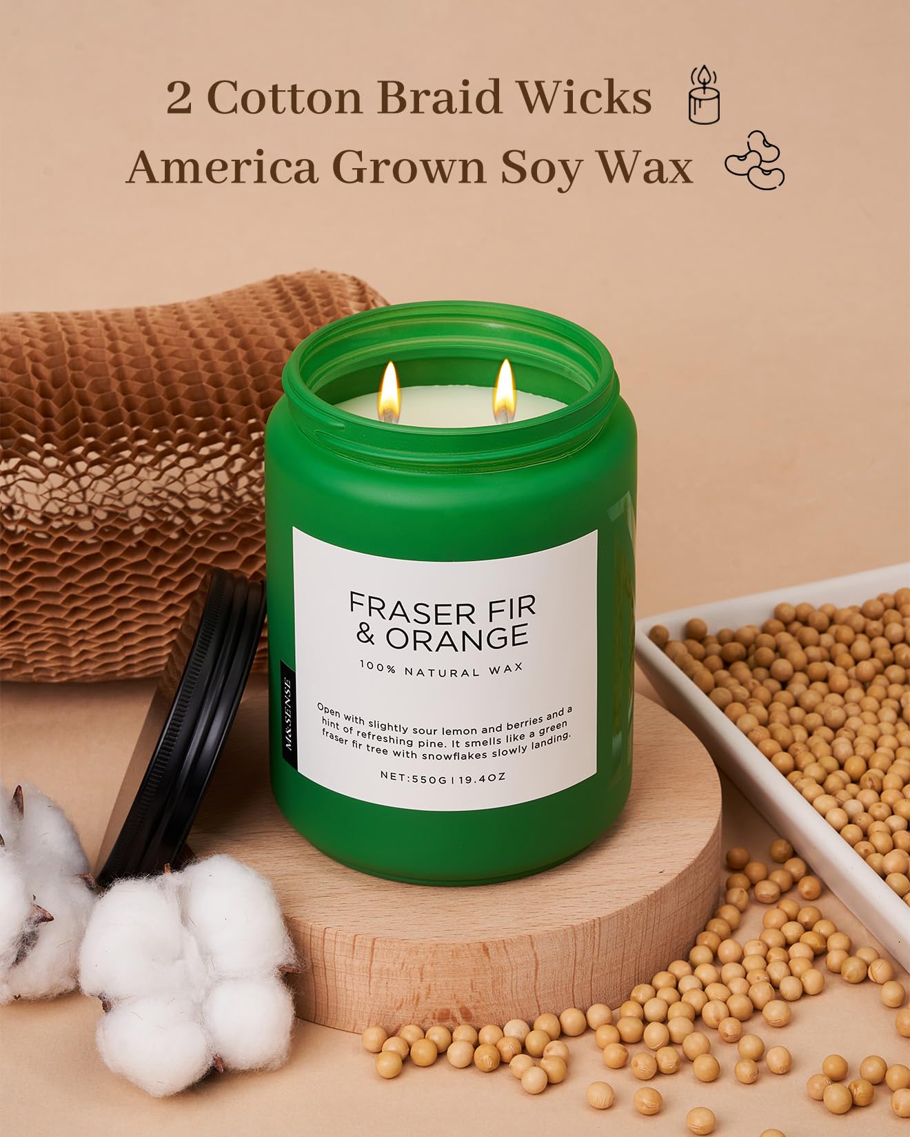 Green candle labeled 'Fraser Fir & Orange' with cotton braid wicks and soy wax on a wooden surface.