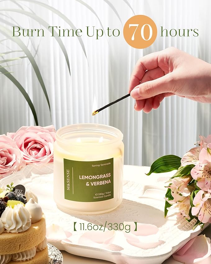 Candle with lemongrass and verbena scent being lit, surrounded by flowers and a cake.