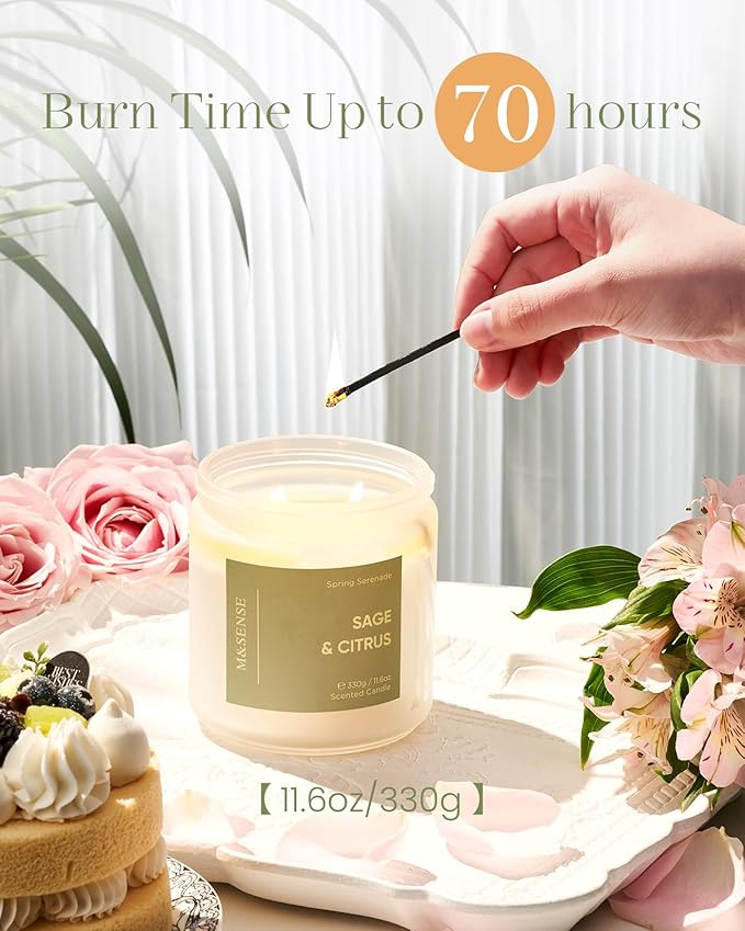 Candle with 'Sage & Citrus' scent being lit by a hand, surrounded by flowers and a cake.