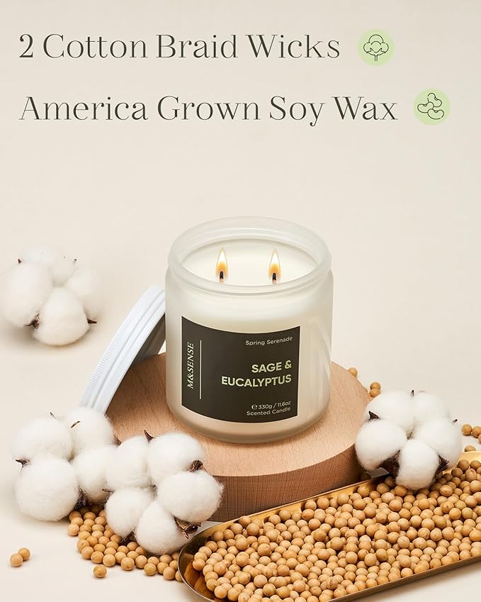 Candle with 'Sage & Eucalyptus' scent on a wooden coaster surrounded by cotton and beans, with text about cotton braid wicks and America grown soy wax.