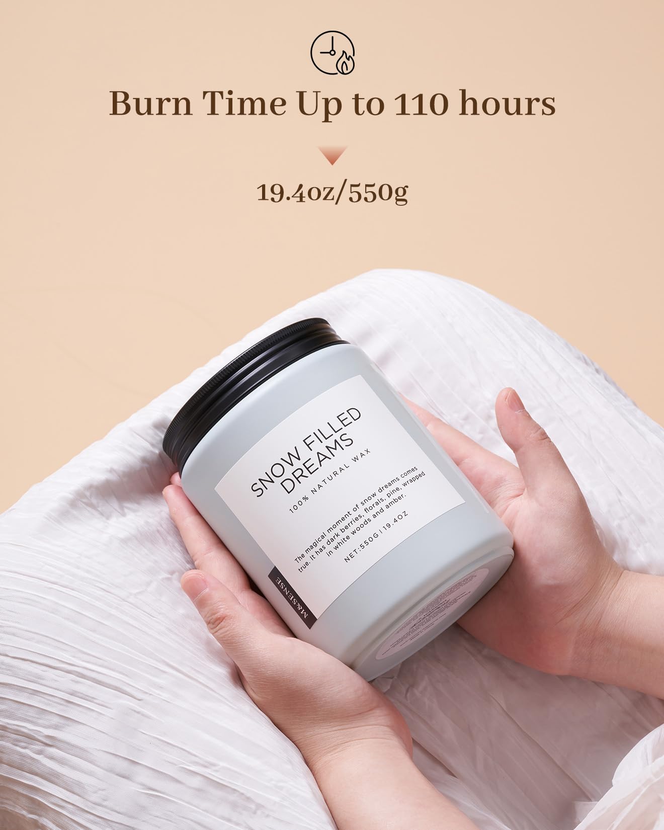 Candle labeled 'Snow Filled Dreams' held by a hand with beige background