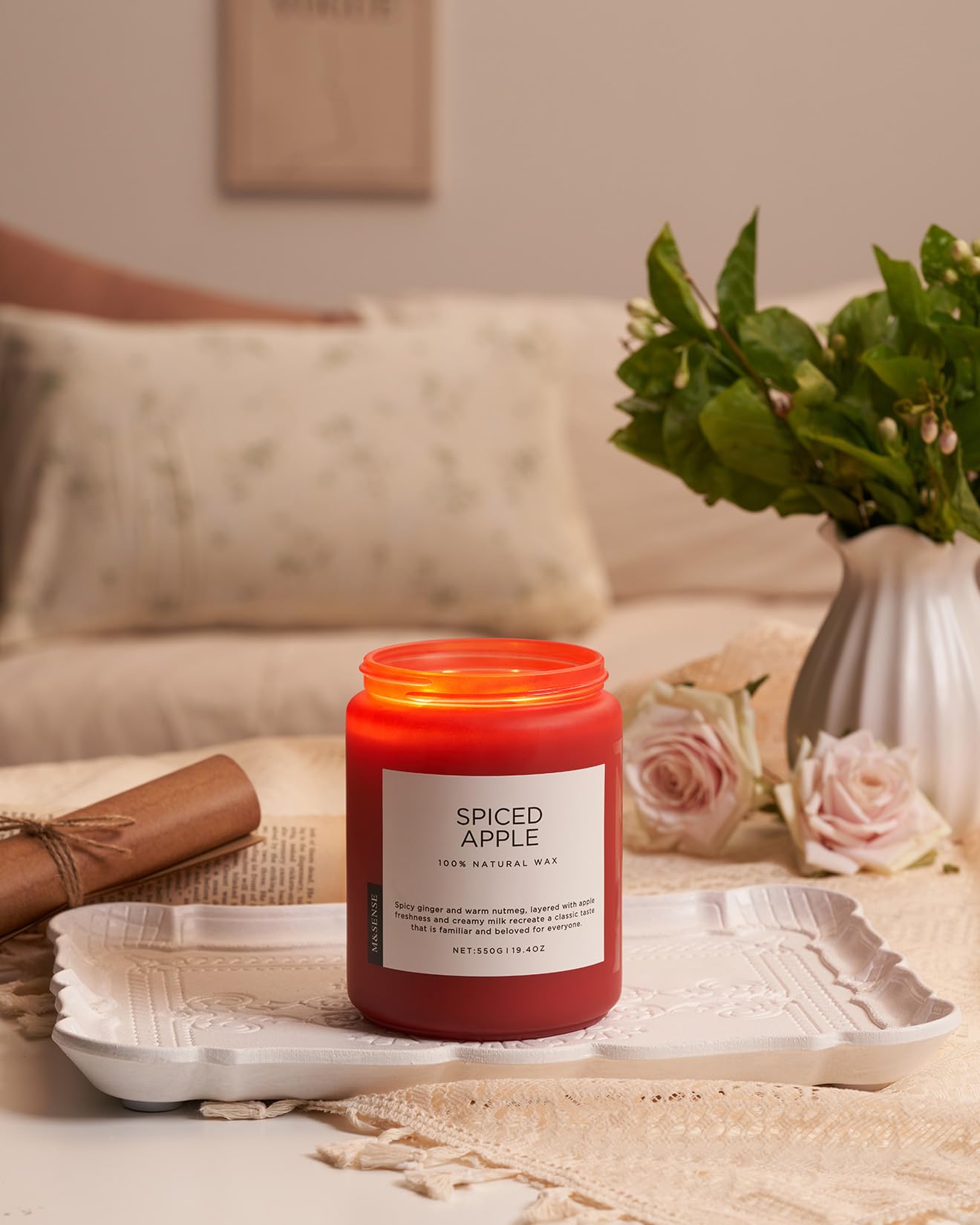 Spiced Apple candle on a table with a vase of flowers and a couch in the background