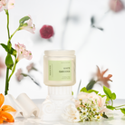 Candle labeled 'White Gardenia' with flowers in the background