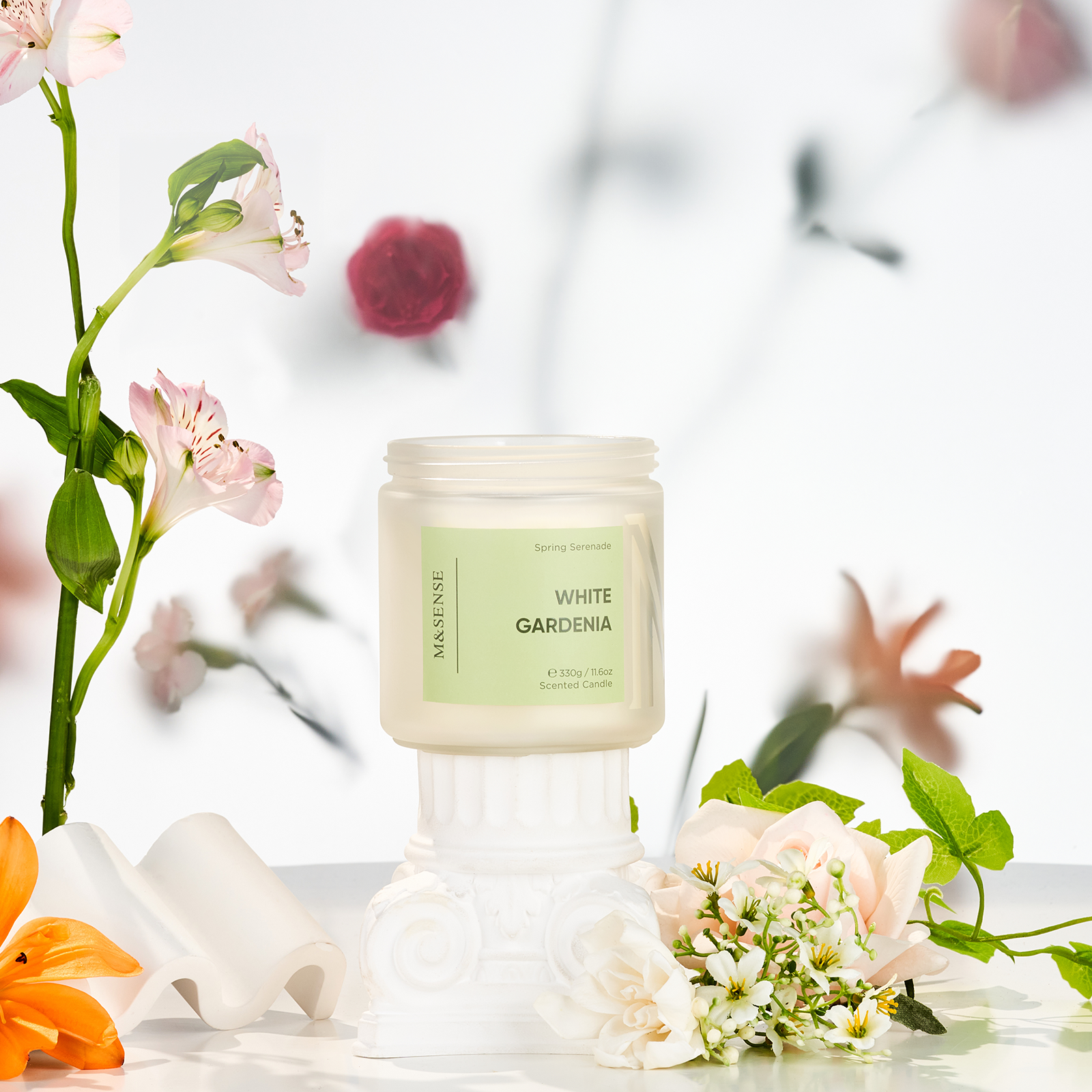 Candle labeled 'White Gardenia' with flowers in the background