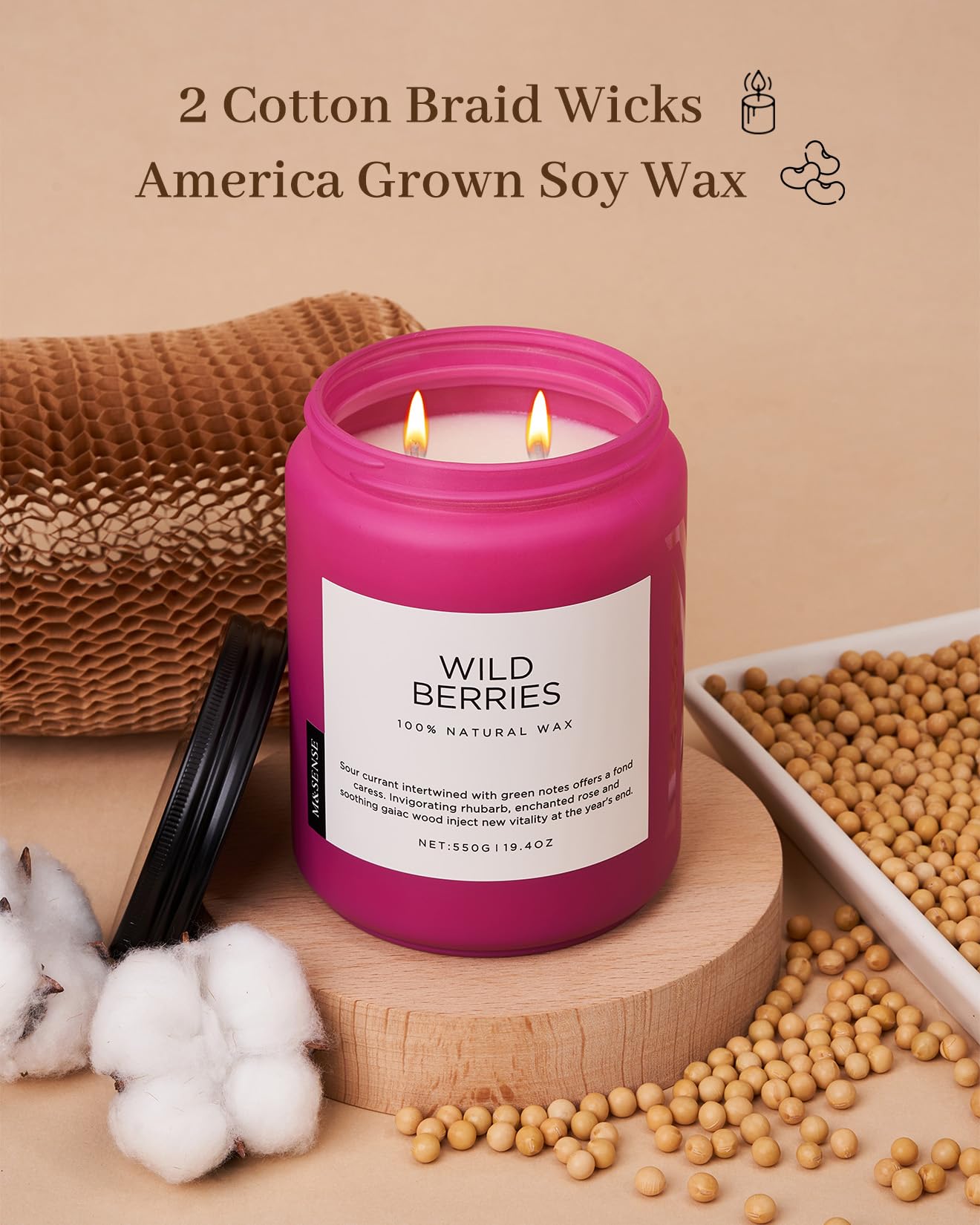 Pink candle with 'Wild Berries' label on a wooden surface with soybeans and cotton.